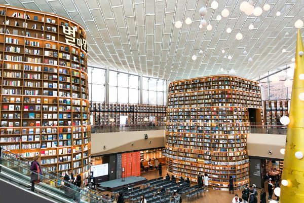 Interior view of a modern South Korean library with towering bookshelves and escalators.